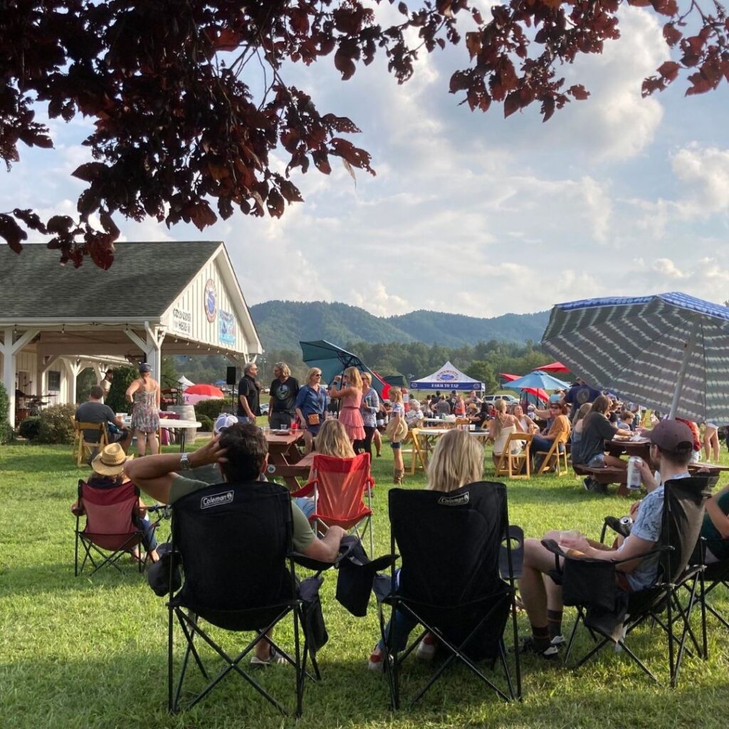 people in lawn chairs in open field with mountains in distance